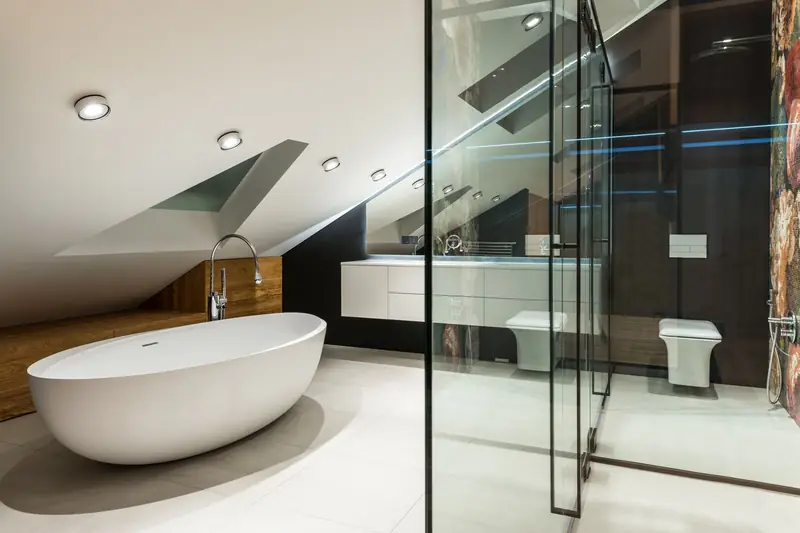 An attic bathroom with a freestanding tub under the eaves and a glazed shower.