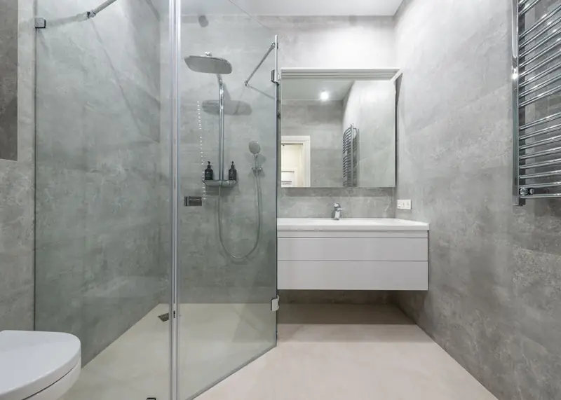 A walk-in shower with concrete-effect tiling and a wall-hung vanity.